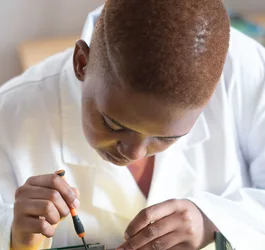 Black electronics technician testing a circuit board