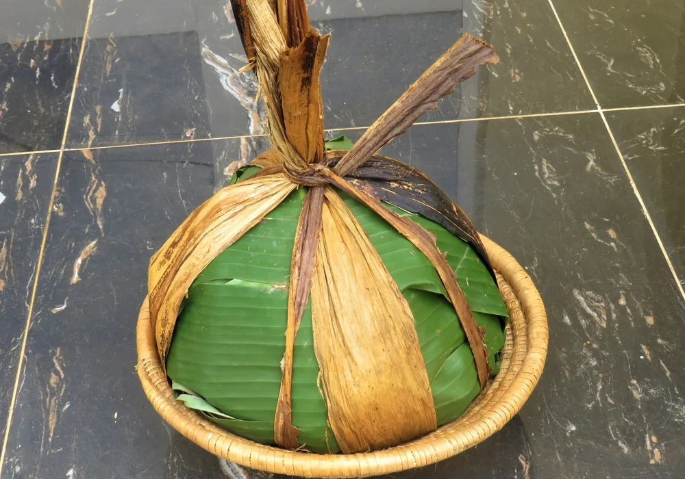 Ugandan matooke wrapped in banana leaves in a woven basket