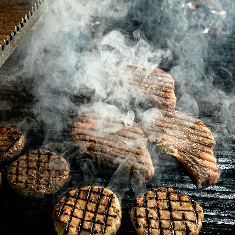 Steaks and burgers cooking on a grill