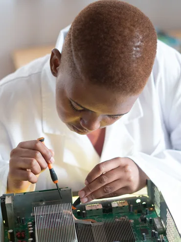 Black electronics technician testing a circuit board