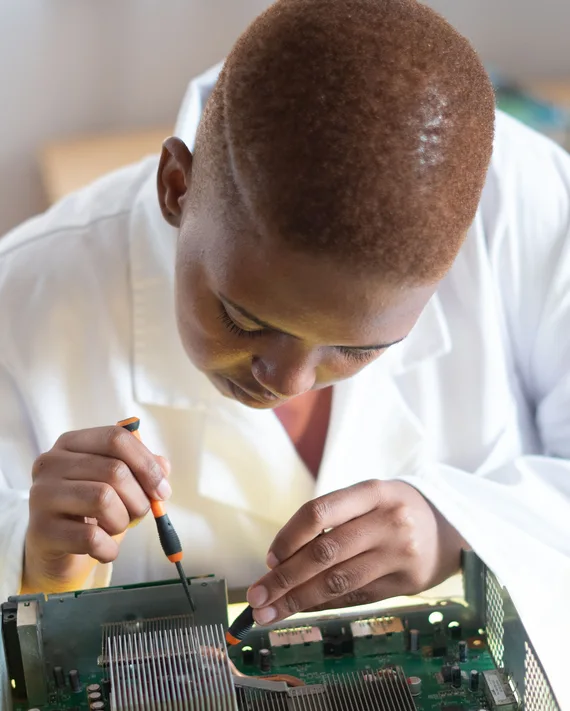 Black electronics technician testing a circuit board