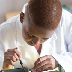 Black electronics technician testing a circuit board