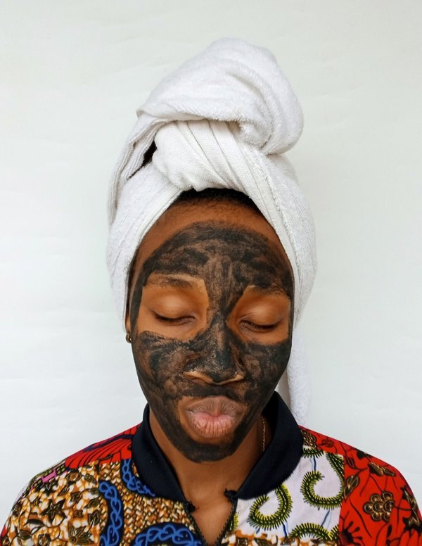 Black woman applying a clay skincare mask