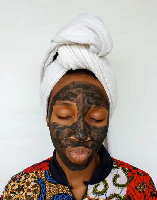 Black woman applying a clay skincare mask
