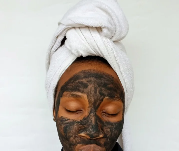 Black woman applying a clay skincare mask