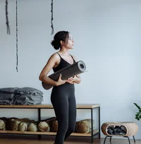 Black woman holding a yoga mat in a studio