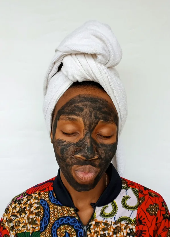 Black woman applying a clay skincare mask