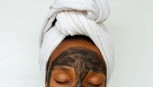 Black woman applying a clay skincare mask