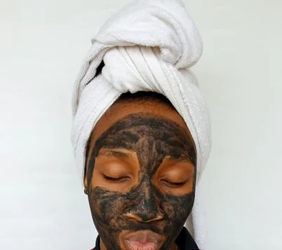 Black woman applying a clay skincare mask