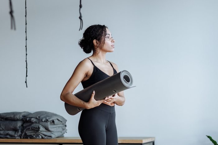 Black woman holding a yoga mat in a studio