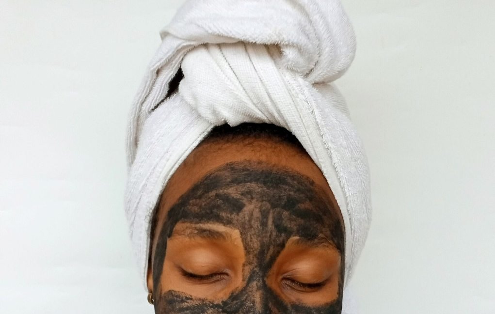 Black woman applying a clay skincare mask