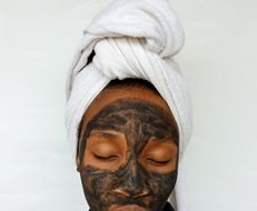 Black woman applying a clay skincare mask