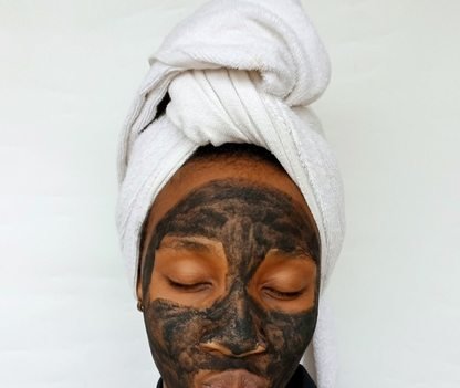Black woman applying a clay skincare mask