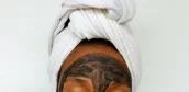 Black woman applying a clay skincare mask