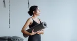 Black woman holding a yoga mat in a studio