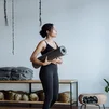 Black woman holding a yoga mat in a studio