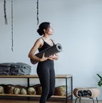 Black woman holding a yoga mat in a studio