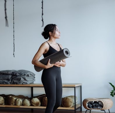 Black woman holding a yoga mat in a studio