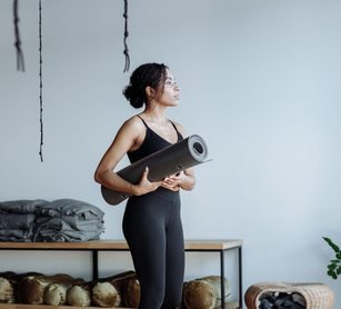 Black woman holding a yoga mat in a studio