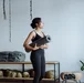 Black woman holding a yoga mat in a studio