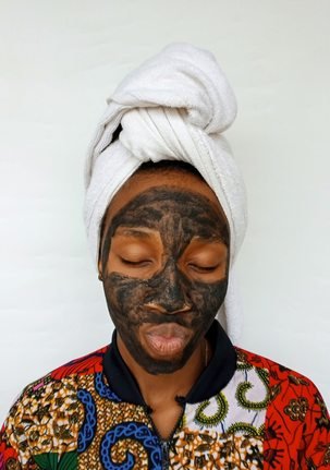 Black woman applying a clay skincare mask