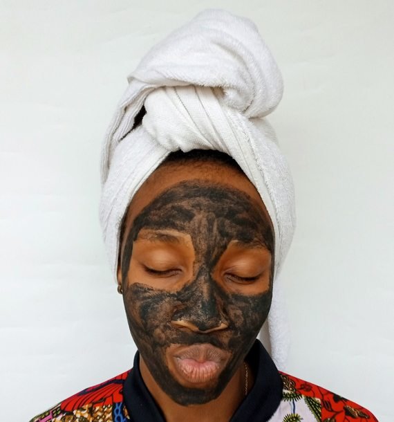 Black woman applying a clay skincare mask