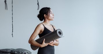 Black woman holding a yoga mat in a studio