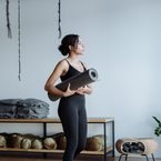 Black woman holding a yoga mat in a studio
