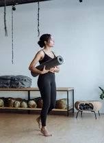 Black woman holding a yoga mat in a studio