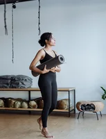 Black woman holding a yoga mat in a studio