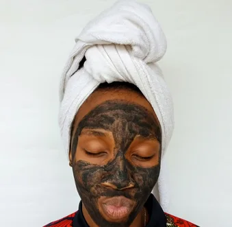 Black woman applying a clay skincare mask