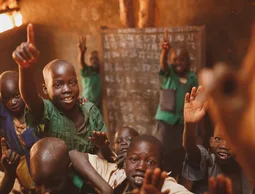 Pupils raising their hands in a Kitgum classroom