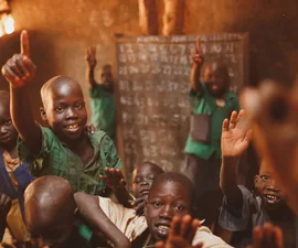 Pupils raising their hands in a Kitgum classroom