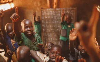 Pupils raising their hands in a Kitgum classroom