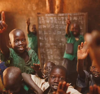Pupils raising their hands in a Kitgum classroom