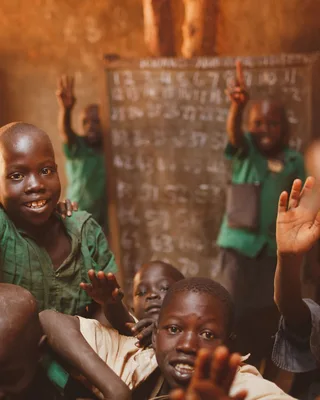 Pupils raising their hands in a Kitgum classroom
