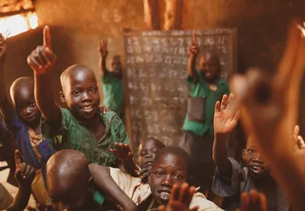 Pupils raising their hands in a Kitgum classroom