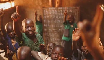 Pupils raising their hands in a Kitgum classroom