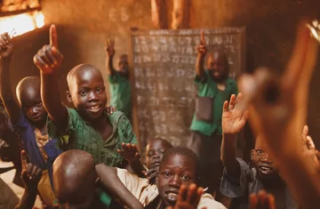 Pupils raising their hands in a Kitgum classroom