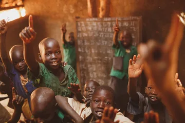 Pupils raising their hands in a Kitgum classroom