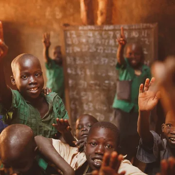 Pupils raising their hands in a Kitgum classroom