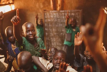 Pupils raising their hands in a Kitgum classroom