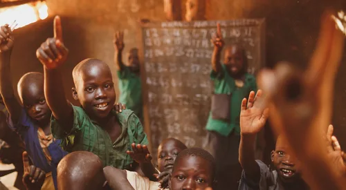 Pupils raising their hands in a Kitgum classroom