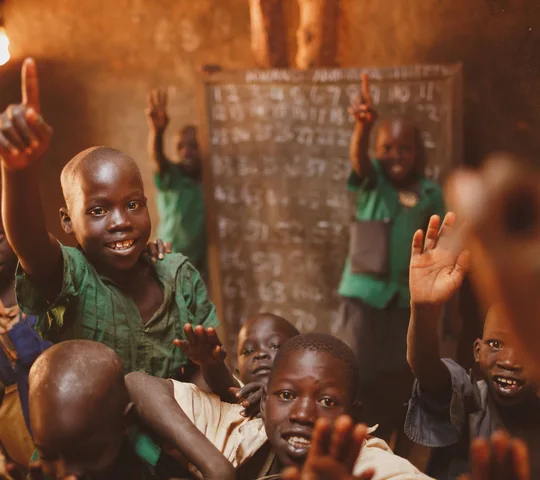 Pupils raising their hands in a Kitgum classroom