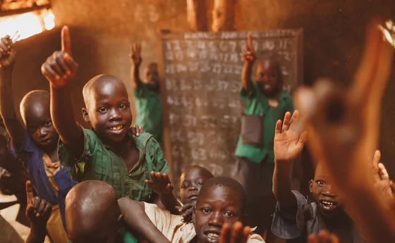 Pupils raising their hands in a Kitgum classroom