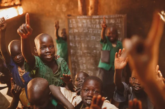 Pupils raising their hands in a Kitgum classroom
