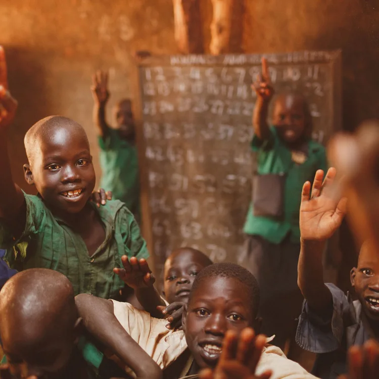Pupils raising their hands in a Kitgum classroom