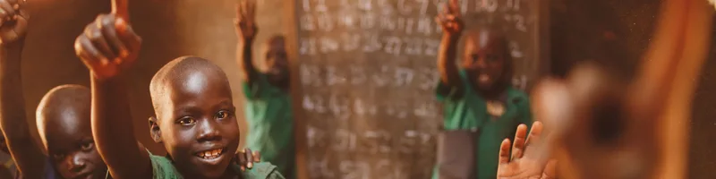 Pupils raising their hands in a Kitgum classroom