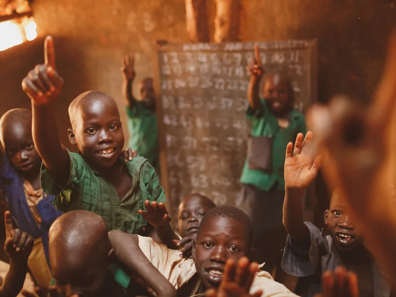 Pupils raising their hands in a Kitgum classroom